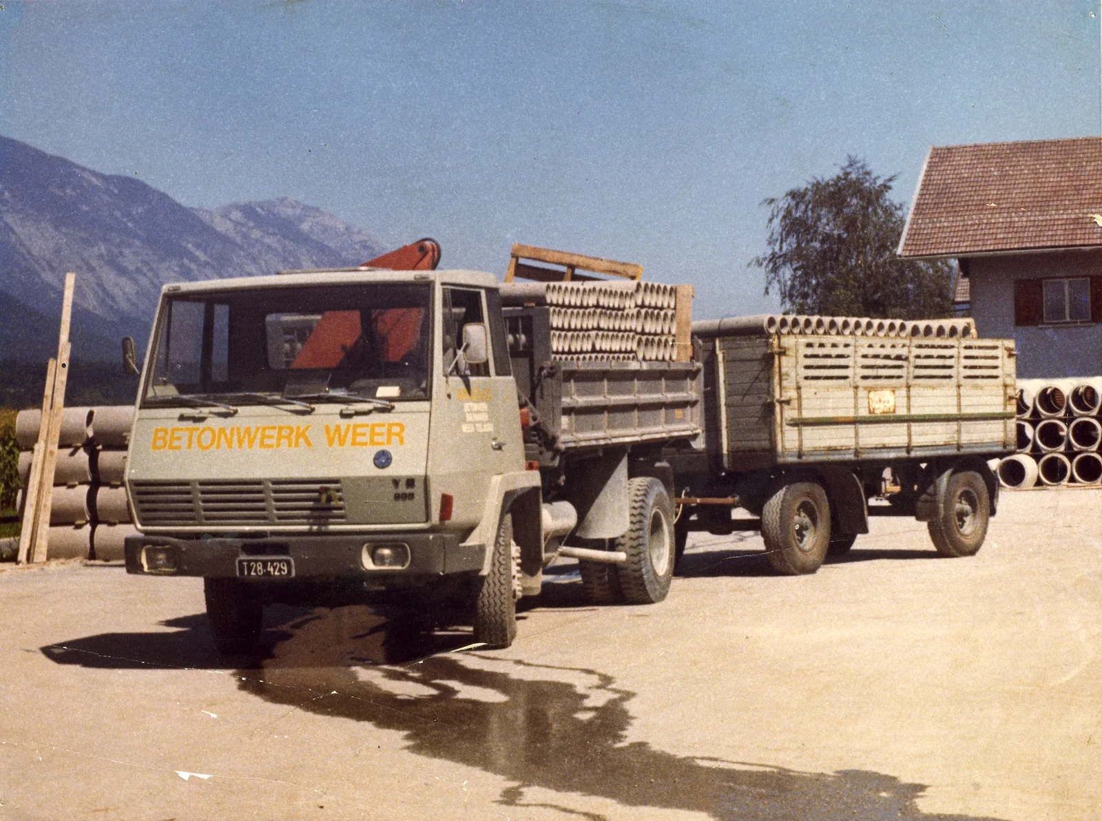 Farbfoto von 1975: ein Lastwagen mit Anhänger voller Betonrohre, auf der Tür steht Betonwerk Weer.